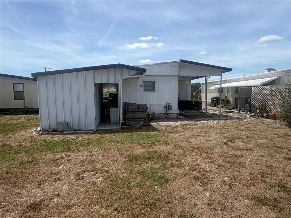 The exterior of a white mobile home features a side entrance and a covered patio — 3020 SEGO LANE, LAKELAND, FL