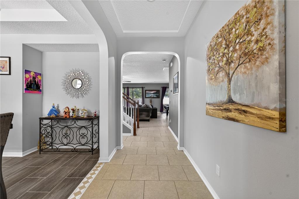 A hallway with tile flooring leads to a living area with a staircase — 736 WOODS LANDING DRIVE, MINNEOLA, FL
