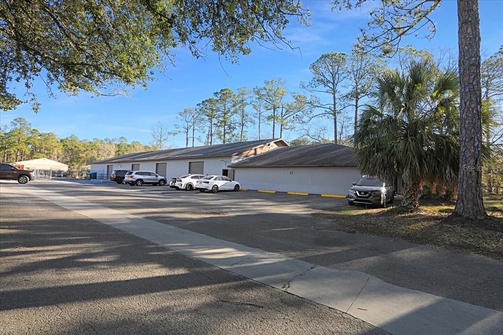 An exterior view of a long, single-story commercial building with a parking lot in front — 2300 NW 71ST PLACE, GAINESVILLE, FL