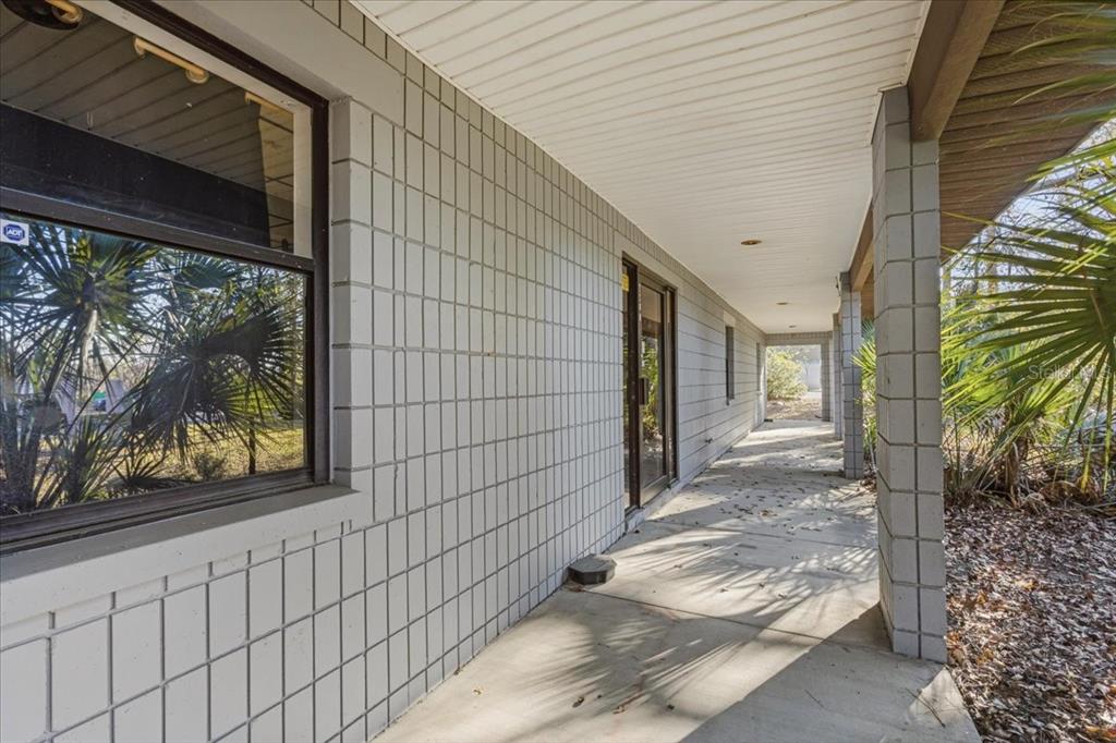 A long concrete porch runs along the side of a house with gray block walls — 2300 NW 71ST PLACE, GAINESVILLE, FL