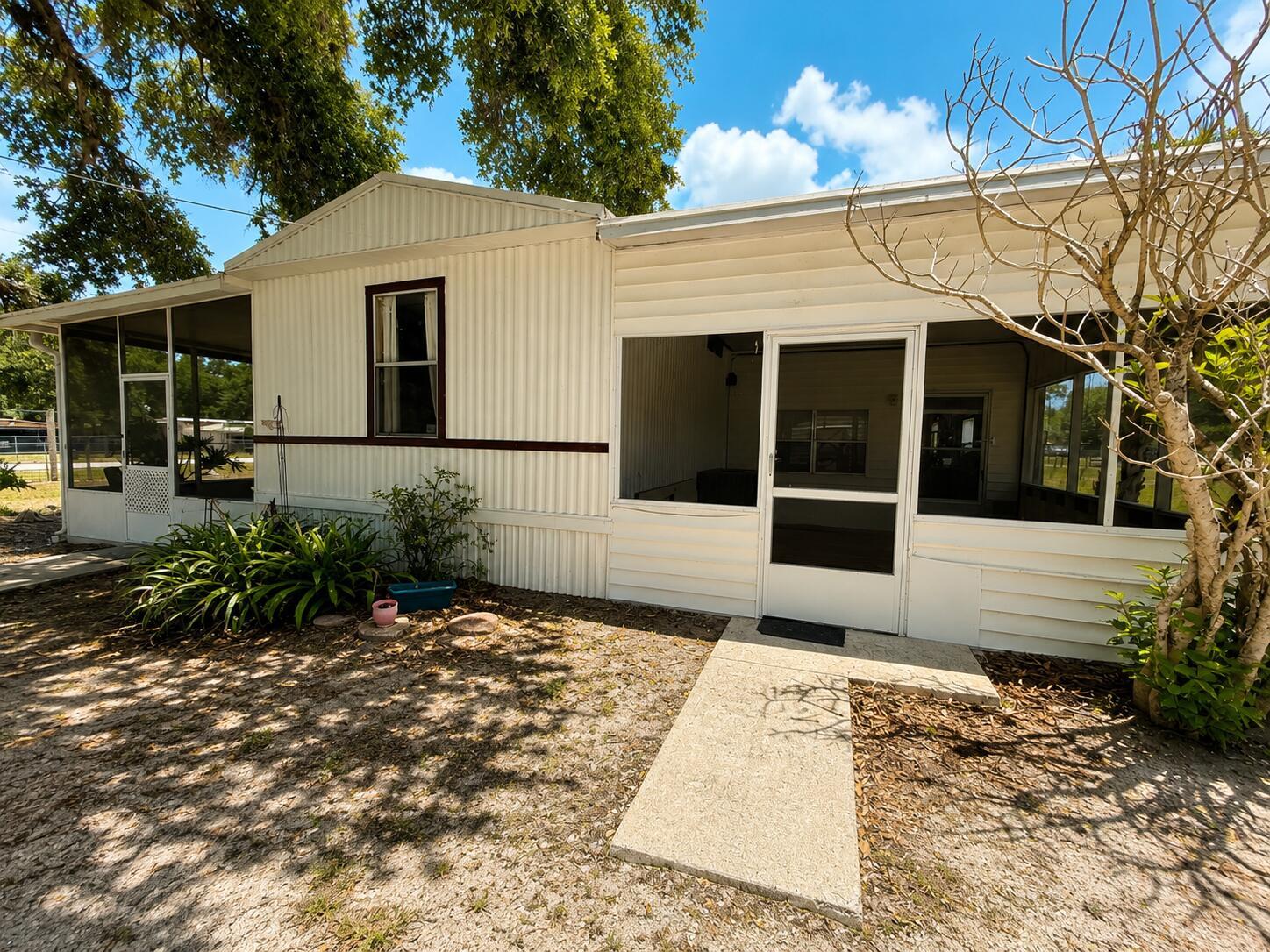 Exterior view of a mobile home with a screened-in porch and a concrete walkway — 482 Palmetto Avenue, FL 33935, FL