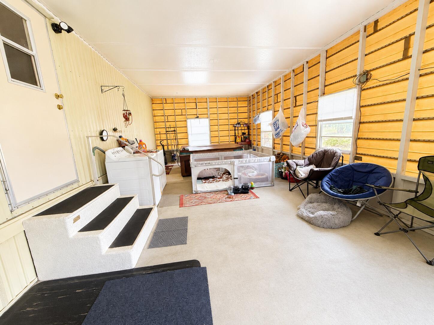 A sunroom features a washing machine, a playpen, folding chairs, and unfinished wood-paneled walls — 482 Palmetto Avenue, FL 33935, FL