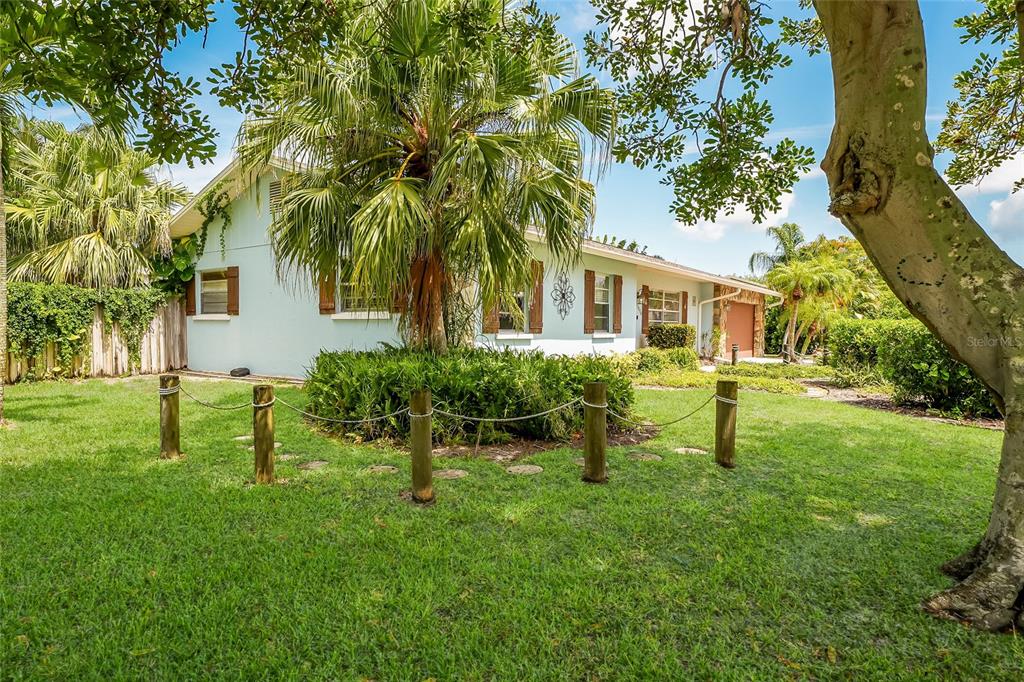 A light blue house with brown shutters sits behind a rope fence and palm tree — 1004 68TH STREET NW, BRADENTON, FL