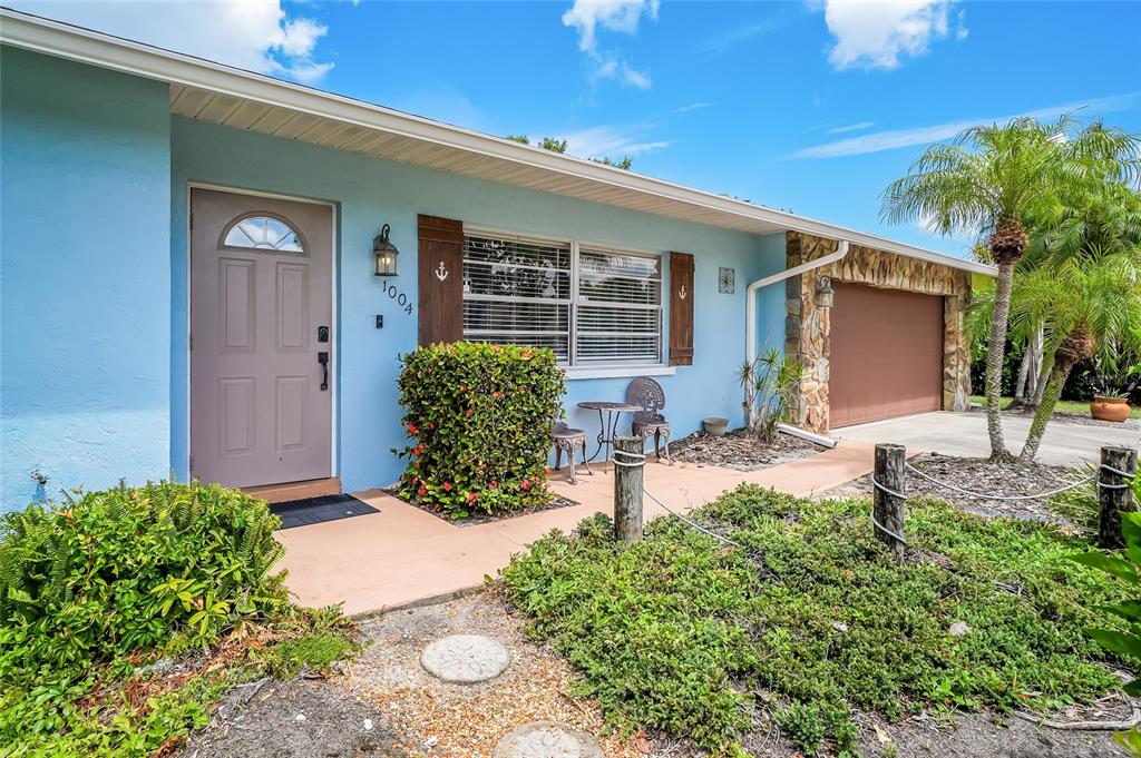 A light blue house exterior features a front door, a garage, and a landscaped yard — 1004 68TH STREET NW, BRADENTON, FL
