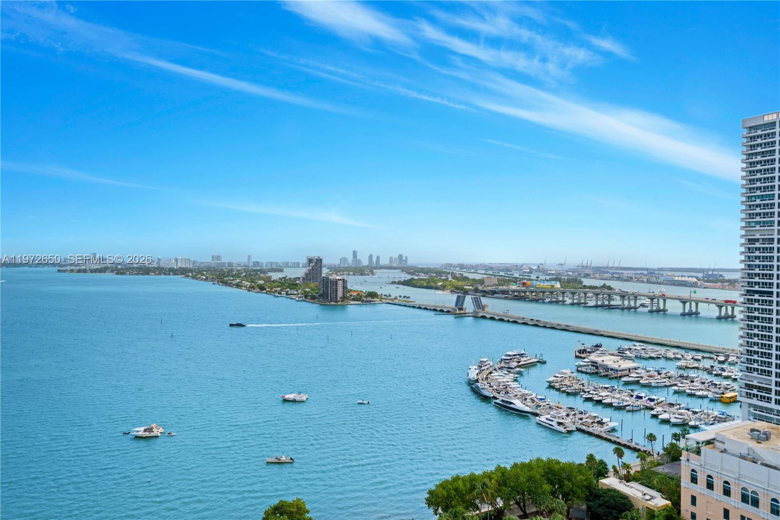 An elevated view of a marina, a drawbridge, and a distant city skyline over water — 488 NE 18th St # 2112, Miami FL 33132, MIAMI, FL