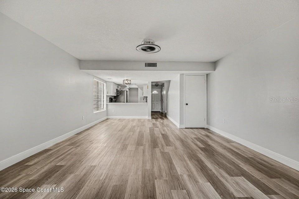 An open-concept living area features light gray walls and wood-look flooring throughout — 3156 FINSTERWALD DRIVE, TITUSVILLE, FL