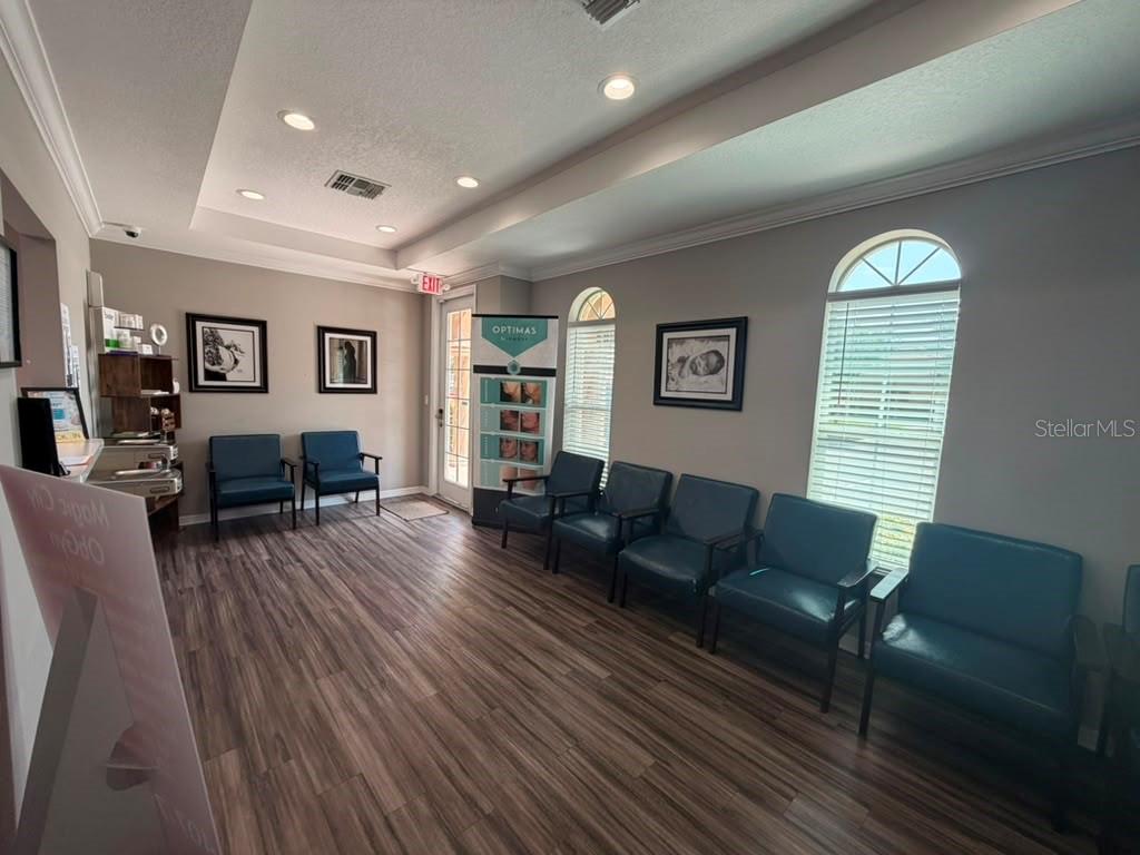 A waiting room features wood-look flooring, blue chairs, and arched windows under a tray ceiling — 3200 HILLSDALE LANE, KISSIMMEE, FL