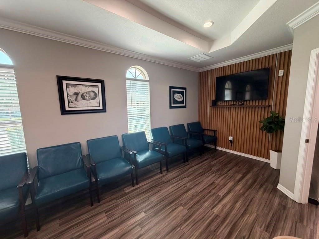 A waiting room features blue chairs, wood-look flooring, and a television on a slatted wall — 3200 HILLSDALE LANE, KISSIMMEE, FL
