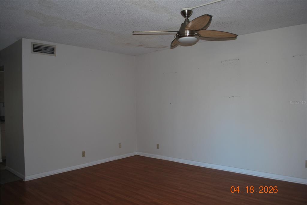 An empty room with wood-look flooring, white walls, a ceiling fan, and a ceiling vent — 9201 TUDOR DRIVE UNIT C215, TAMPA, FL