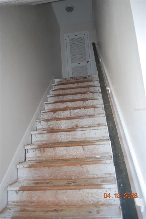 A staircase with worn white paint leads to a louvered door at the top — 9201 TUDOR DRIVE UNIT C215, TAMPA, FL