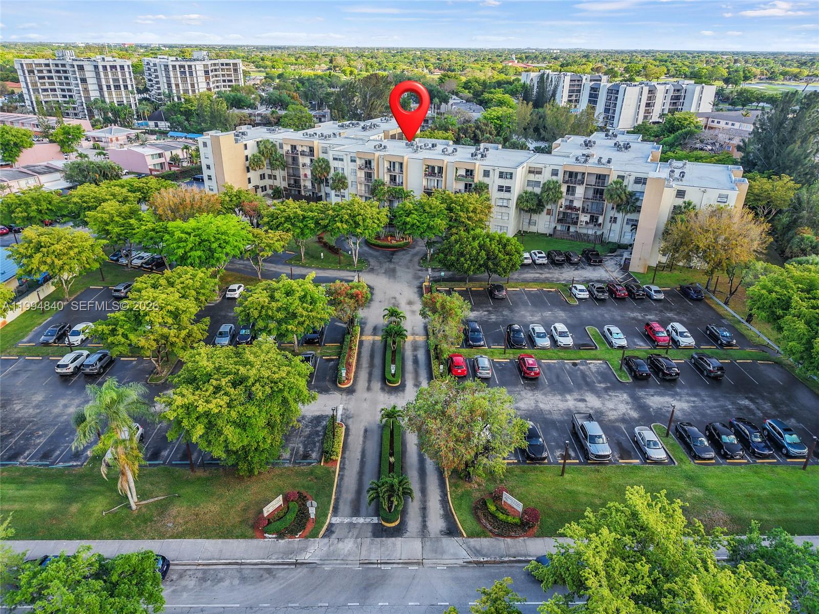 An aerial view shows a multi-story apartment building surrounded by parking lots and trees — 14250 SW 62nd St # 402, Miami FL 33183, MIAMI, FL