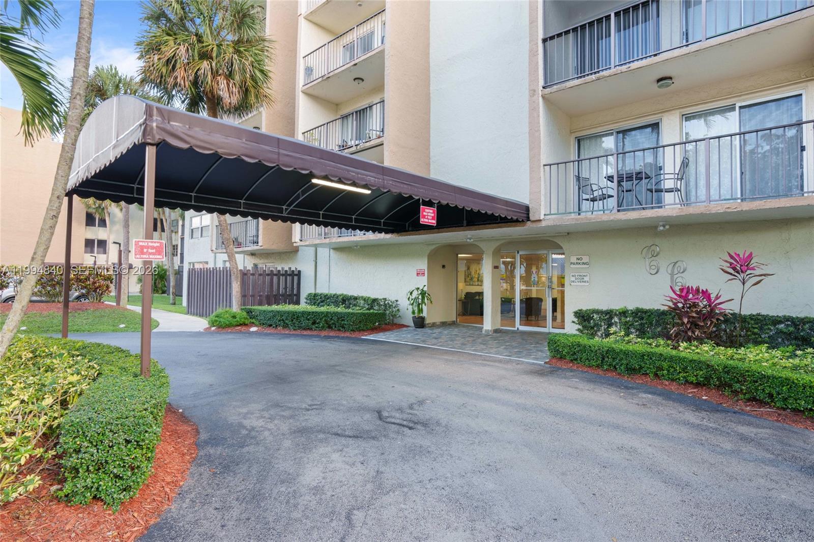 The exterior of a multi-story apartment building features a covered driveway entrance and balconies — 14250 SW 62nd St # 402, Miami FL 33183, MIAMI, FL