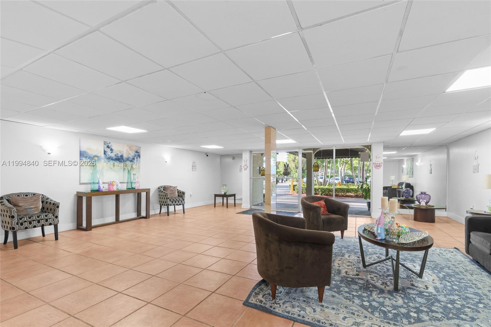 A lobby area features tile flooring, a drop ceiling, several armchairs, and a glass entrance — 14250 SW 62nd St # 402, Miami FL 33183, MIAMI, FL
