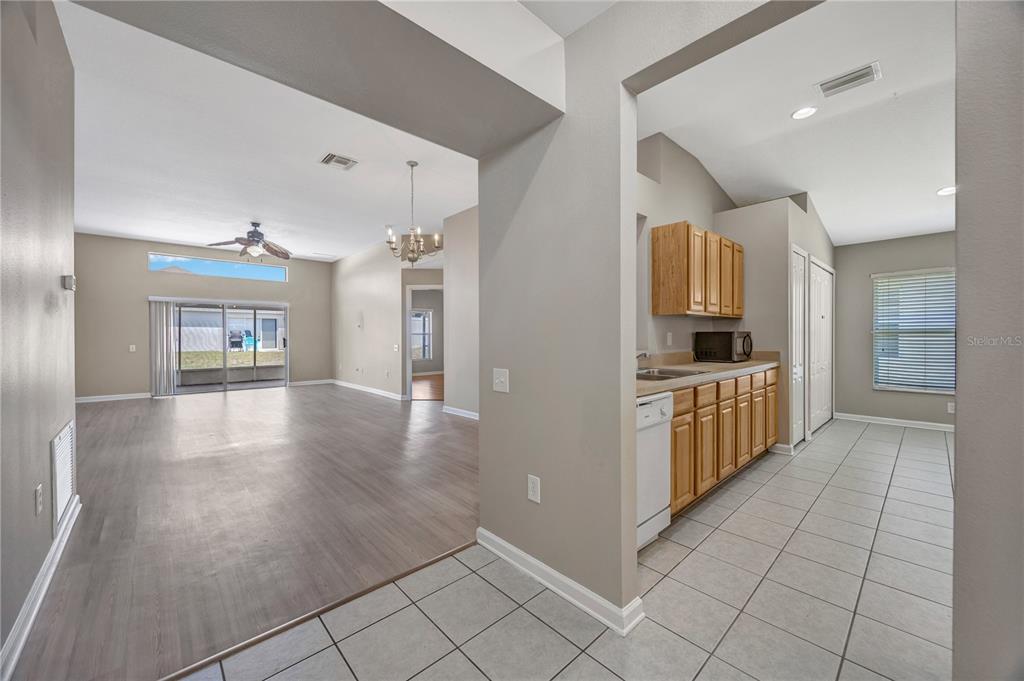 A view from a tiled kitchen into a living area with wood-look flooring — 30435 ANNADALE DRIVE, WESLEY CHAPEL, FL