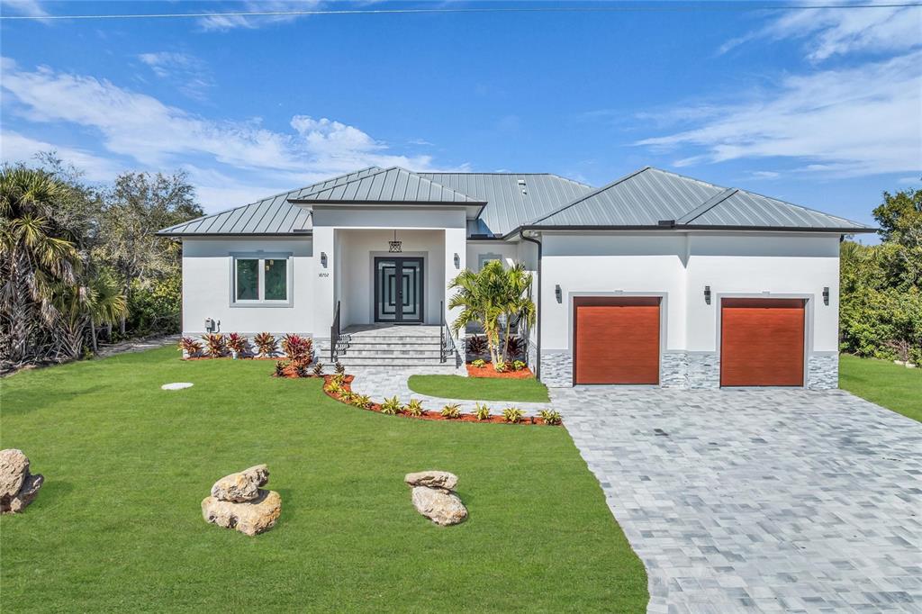 An aerial view shows a single-story house with a metal roof and two-car garage — 18702 ARAPAHOE CIRCLE, PORT CHARLOTTE, FL
