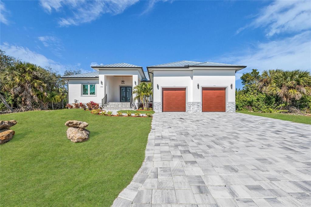 An aerial view shows a waterfront house with a metal roof and a screened lanai — 18702 ARAPAHOE CIRCLE, PORT CHARLOTTE, FL