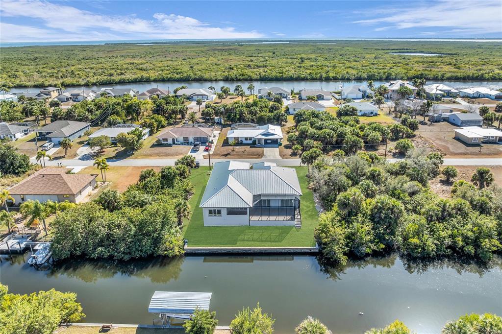 A modern white house with a metal roof, two garage doors, and large front yard rocks — 18702 ARAPAHOE CIRCLE, PORT CHARLOTTE, FL