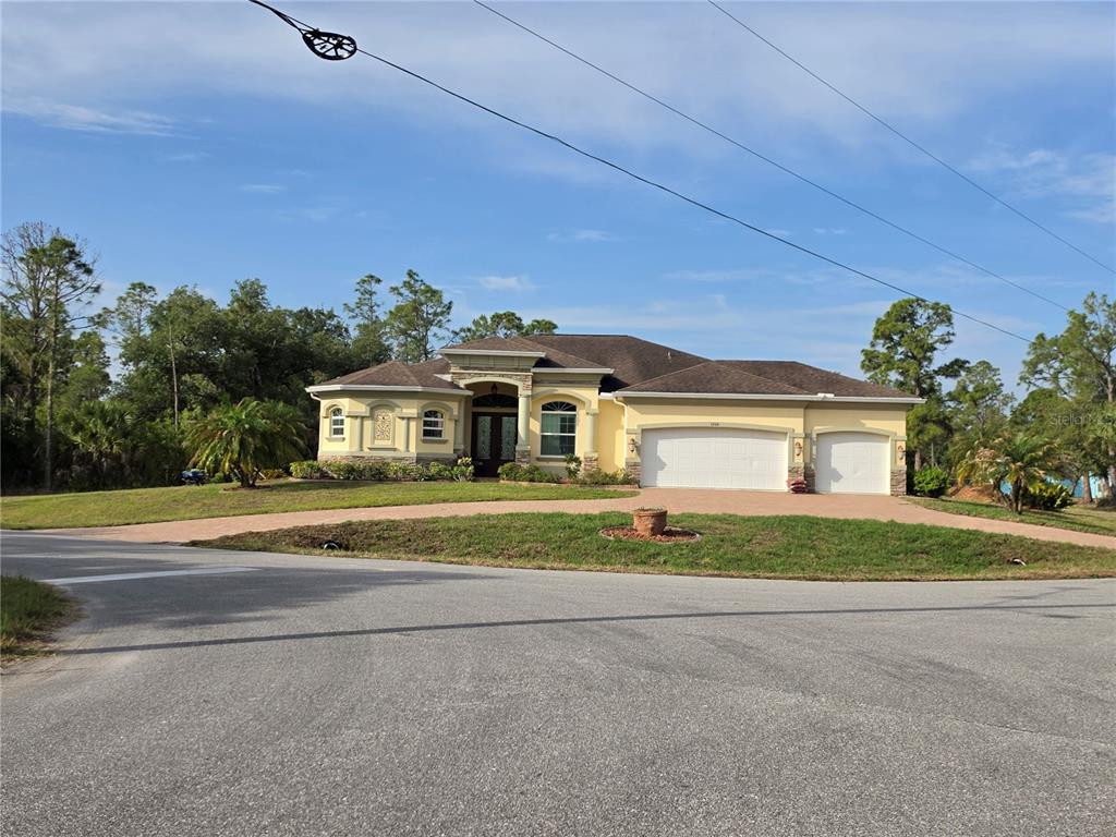 A single-story yellow house with a three-car garage and a paved driveway — 1193 HAMMACHER LANE, PORT CHARLOTTE, FL