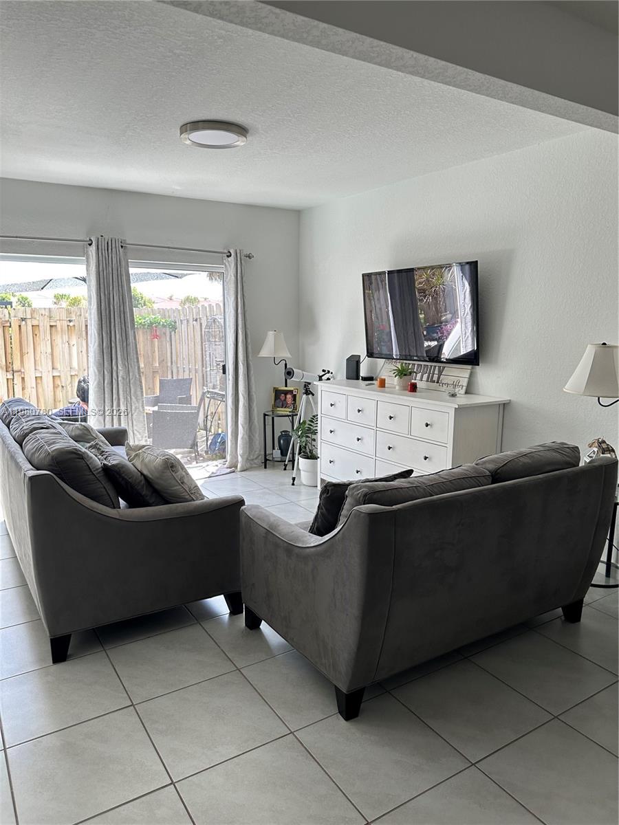 A living room features two grey sofas, a white dresser, and a sliding glass door — 497 NE 4th St, Florida City FL 33034, FLORIDA CITY, FL