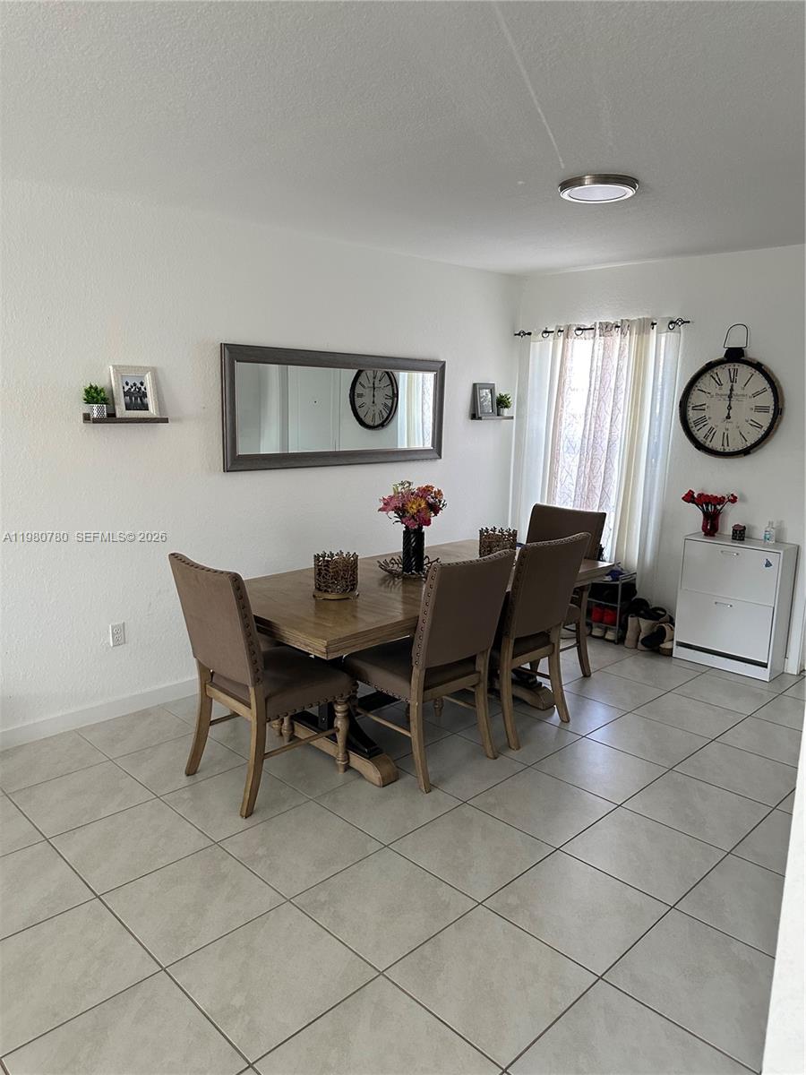 A dining room features a wooden table, six upholstered chairs, a mirror, and wall clocks — 497 NE 4th St, Florida City FL 33034, FLORIDA CITY, FL