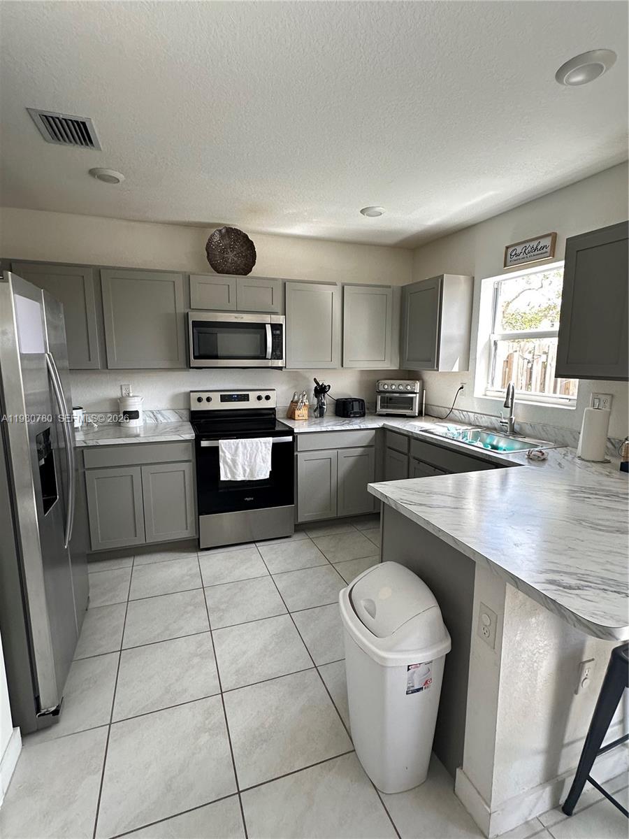 A kitchen features gray cabinets, stainless steel appliances, and white marble-patterned countertops — 497 NE 4th St, Florida City FL 33034, FLORIDA CITY, FL