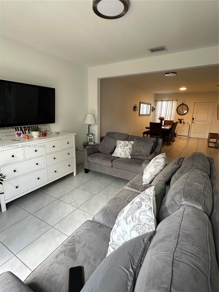 A living room with gray sofas, a white dresser, and a television faces a dining area — 497 NE 4th St, Florida City FL 33034, FLORIDA CITY, FL