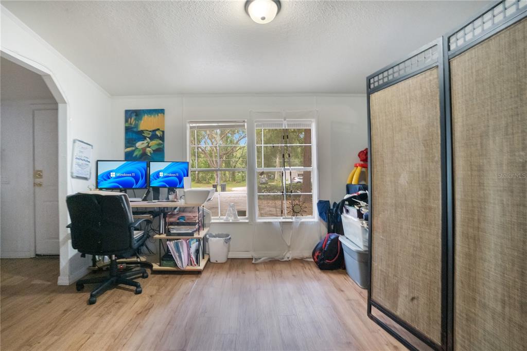 A home office features a dual-monitor desk, wood-look flooring, and a folding privacy screen — 2322 STATE PARK ROAD, LAKELAND, FL