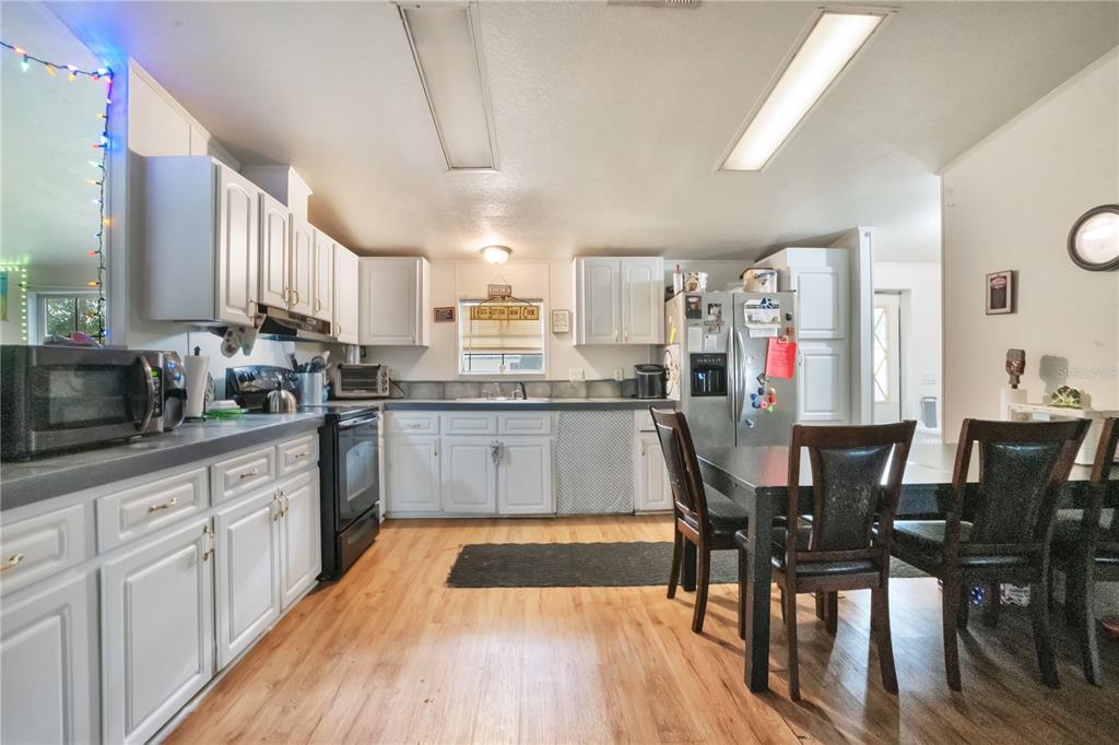 A kitchen features white cabinets, dark countertops, wood-look flooring, and a dining table — 2322 STATE PARK ROAD, LAKELAND, FL