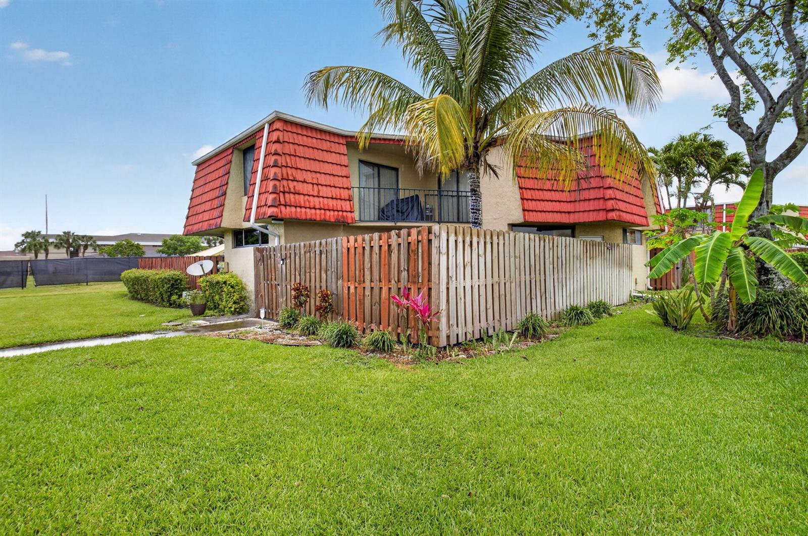 A two-story building with a red mansard roof and a wooden privacy fence — 8385 Trent Court # D, Boca Raton FL 33433, BOCA RATON, FL