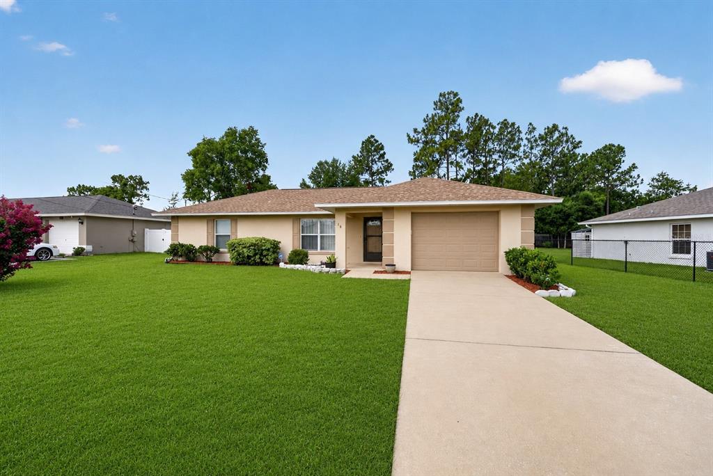 A single-story house with a tan exterior, a brown shingled roof, and a concrete driveway — 16 FIR TRAIL COURSE, OCALA, FL