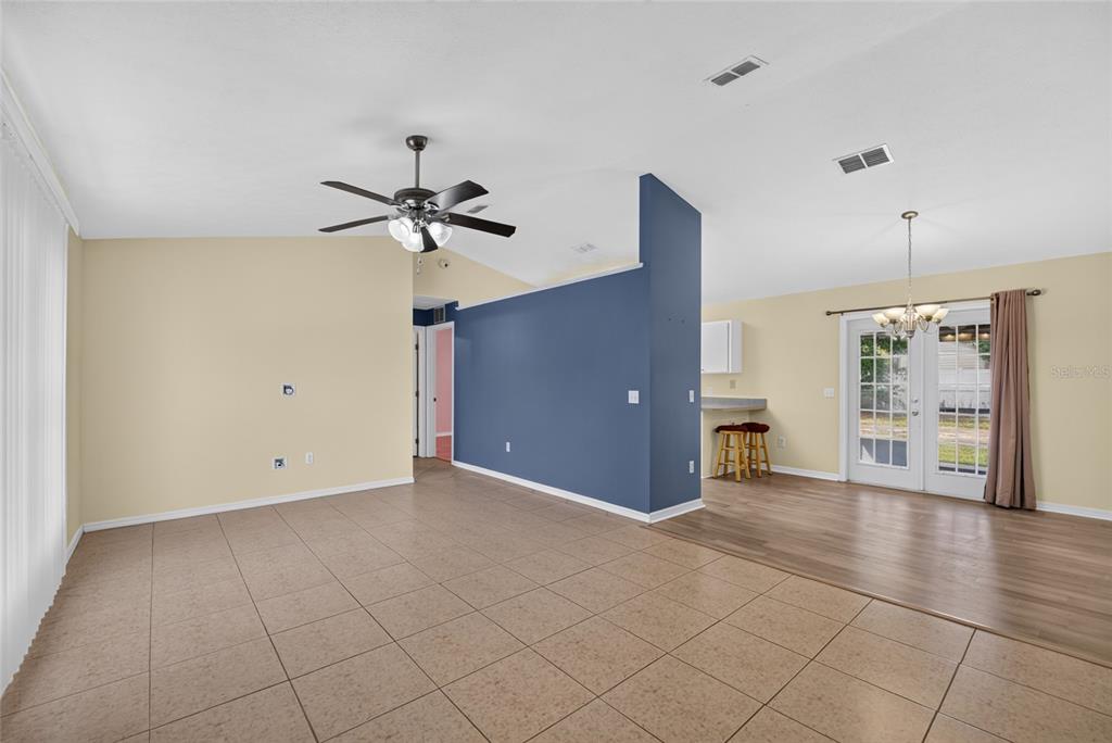 A living room with tile flooring, a blue accent wall, and an adjacent dining area — 16 FIR TRAIL COURSE, OCALA, FL