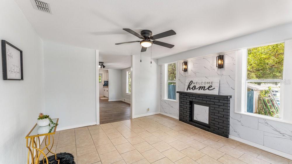 A living room features a black brick fireplace, marble-look wall tiles, and tile flooring — 912 E CAROLINA AVE, DELAND, FL