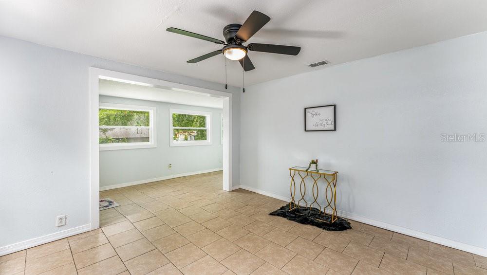 A room with light blue walls, tile flooring, a ceiling fan, and a gold console table — 912 E CAROLINA AVE, DELAND, FL