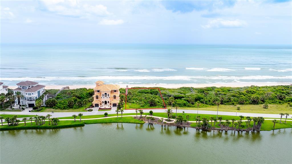 An aerial view shows a vacant oceanfront lot outlined in red next to a large house — 73 CALLE DEL SUR Lot 50, PALM COAST, FL