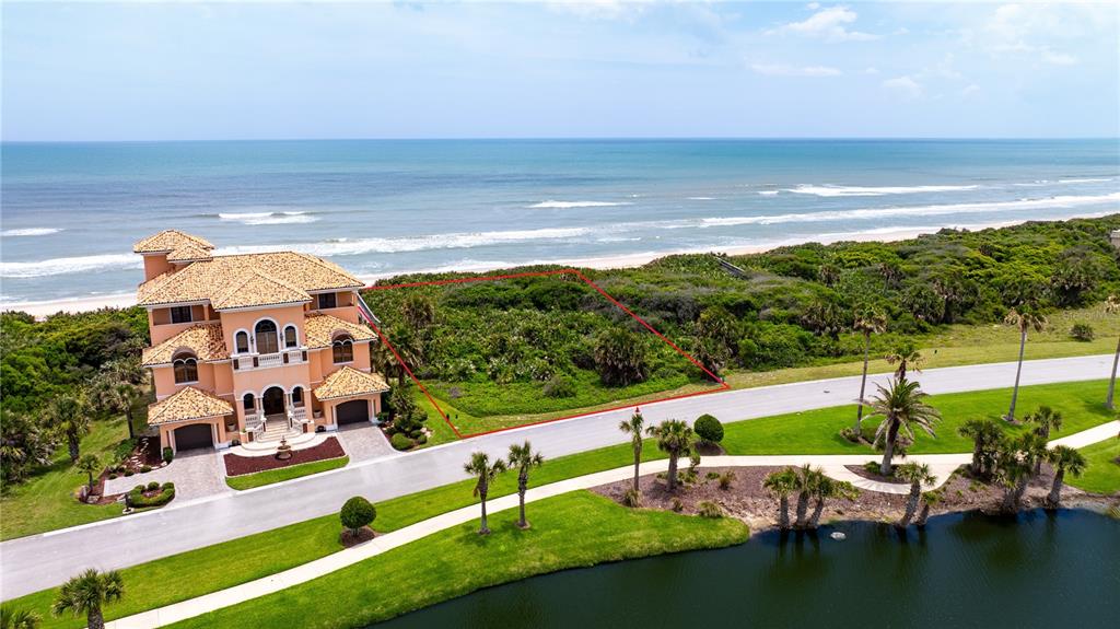 An aerial view shows a vacant oceanfront lot next to a large multi-story house — 73 CALLE DEL SUR Lot 50, PALM COAST, FL