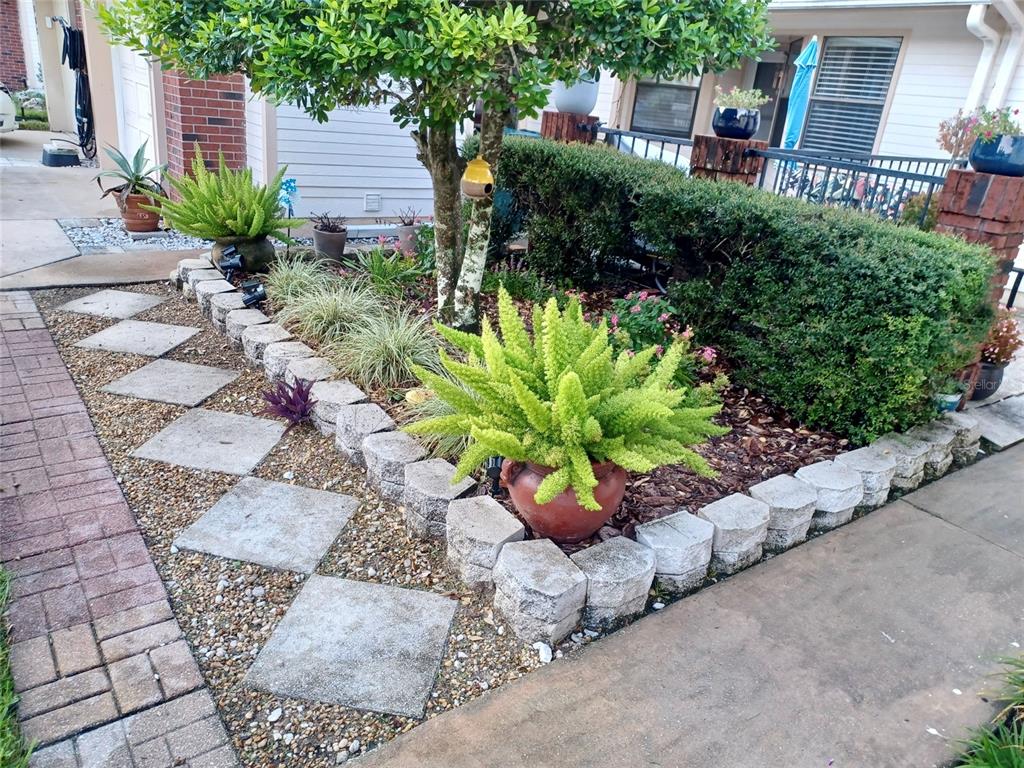 A landscaped front yard features a stone-bordered garden bed with a tree and potted plants — 3929 NE 21ST LANE, OCALA, FL
