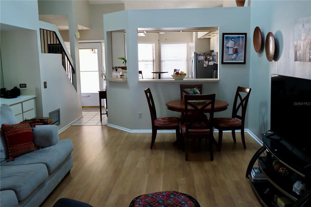 A living room with light wood flooring leads to a dining area and kitchen pass-through — 3929 NE 21ST LANE, OCALA, FL