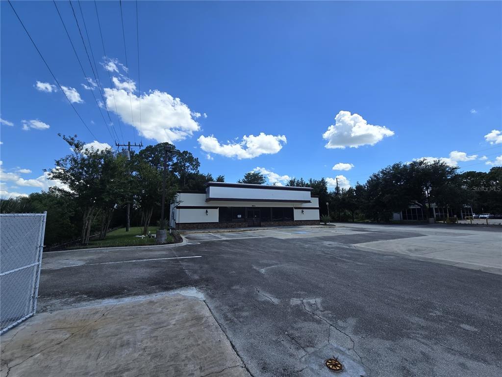 A single-story commercial building with a large parking lot under a blue sky — 8801 20TH STREET, VERO BEACH, FL