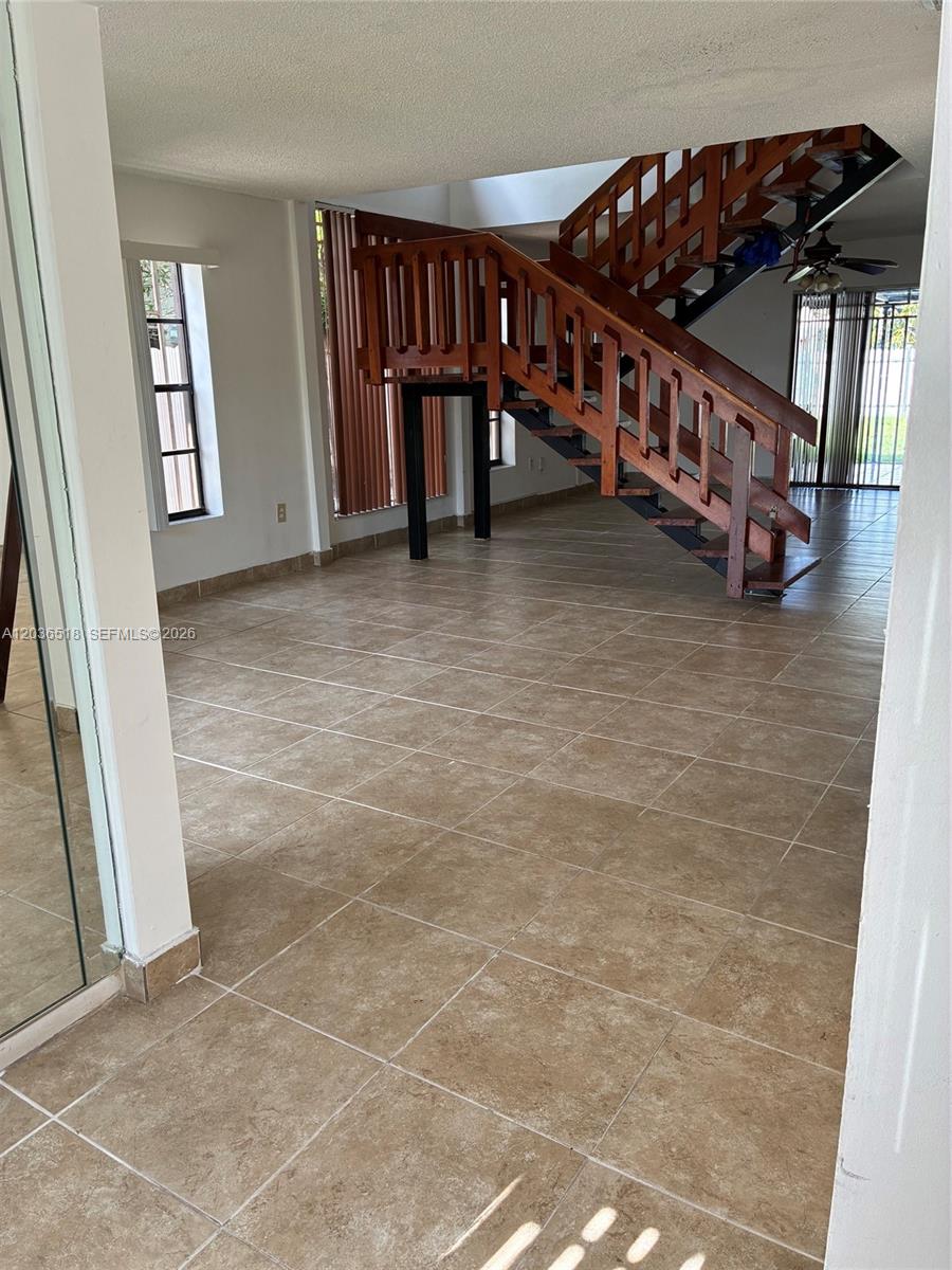 A living area features large beige floor tiles and a prominent wooden staircase — 2441 SW 111th Ave # 2441, Miami FL 33165, MIAMI, FL