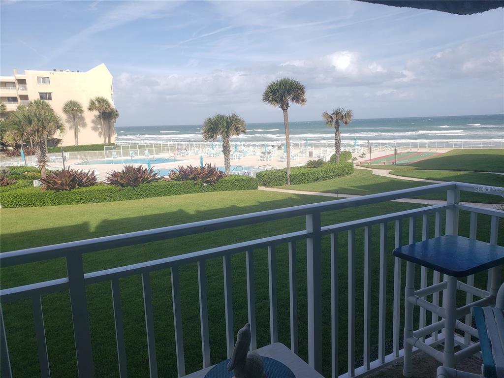 A balcony overlooks a grassy lawn, a swimming pool, and the ocean beyond — 4501 S ATLANTIC AVENUE UNIT 205, NEW SMYRNA BEACH, FL