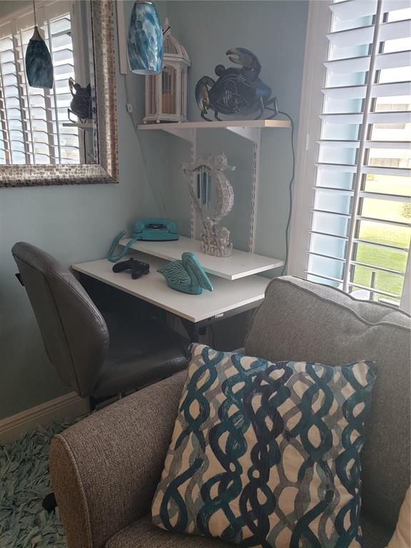 A small home office corner features a desk, shelving, a chair, and coastal decor — 4501 S ATLANTIC AVENUE UNIT 205, NEW SMYRNA BEACH, FL