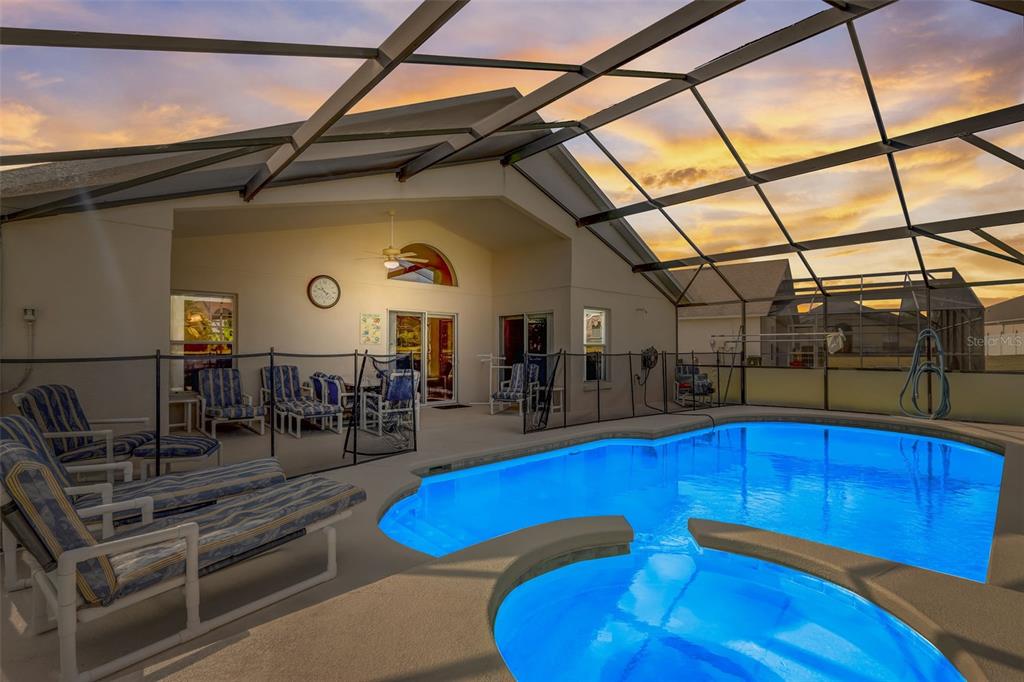 A swimming pool and hot tub sit inside a screened lanai with patio furniture — 523 BALMORAL DRIVE, DAVENPORT, FL