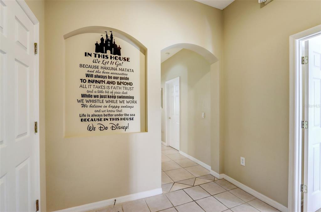 A hallway features a beige arched wall niche decorated with Disney-themed wall decals — 523 BALMORAL DRIVE, DAVENPORT, FL