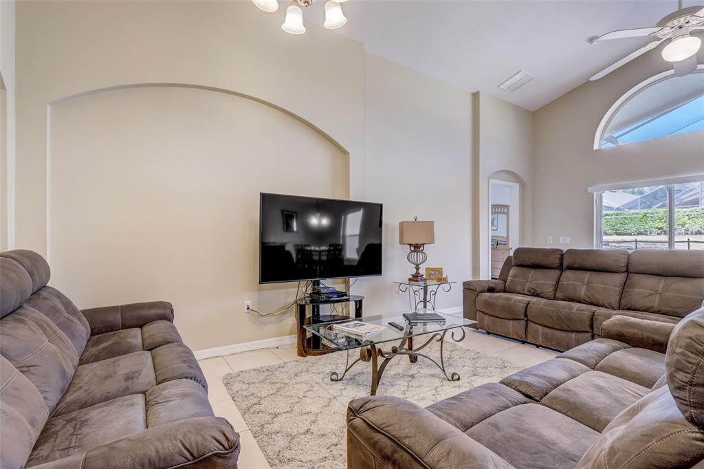 A living room features two brown reclining sofas, a glass coffee table, and a television — 523 BALMORAL DRIVE, DAVENPORT, FL