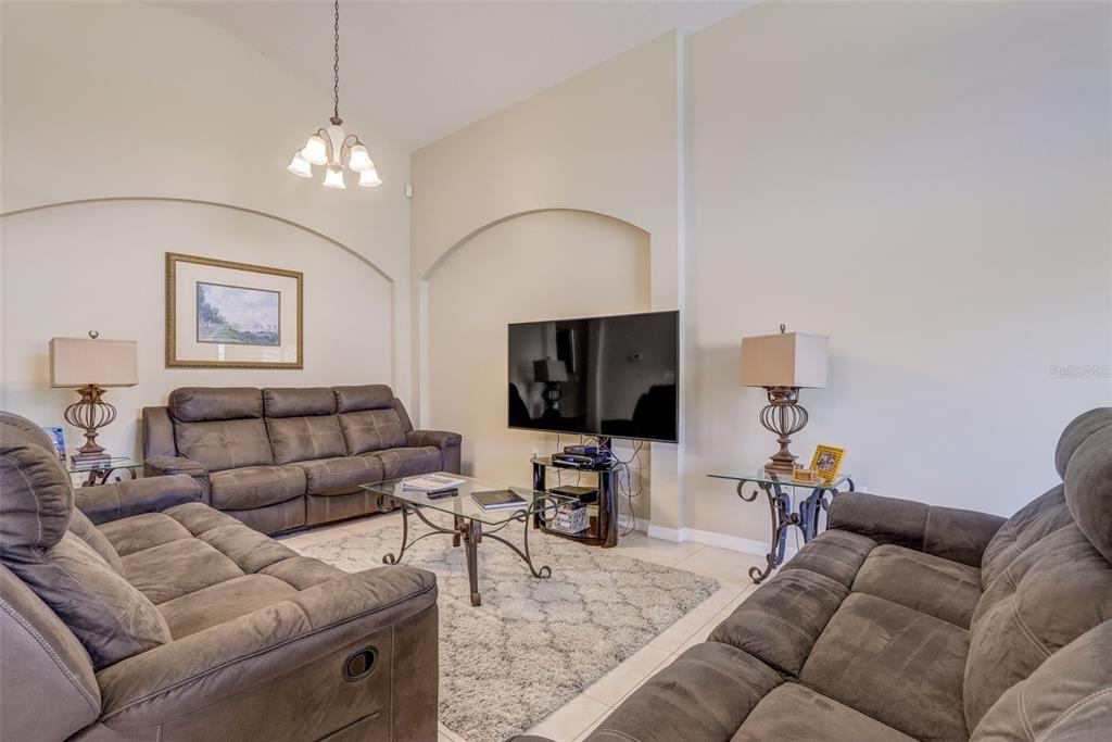 A living room features two brown reclining sofas, a glass coffee table, and arched wall niches — 523 BALMORAL DRIVE, DAVENPORT, FL