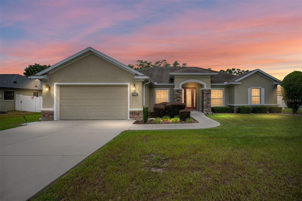 A single-story house with a beige stucco exterior, a two-car garage, and a stone-accented entryway — 9654 SW 40TH TERRACE, OCALA, FL
