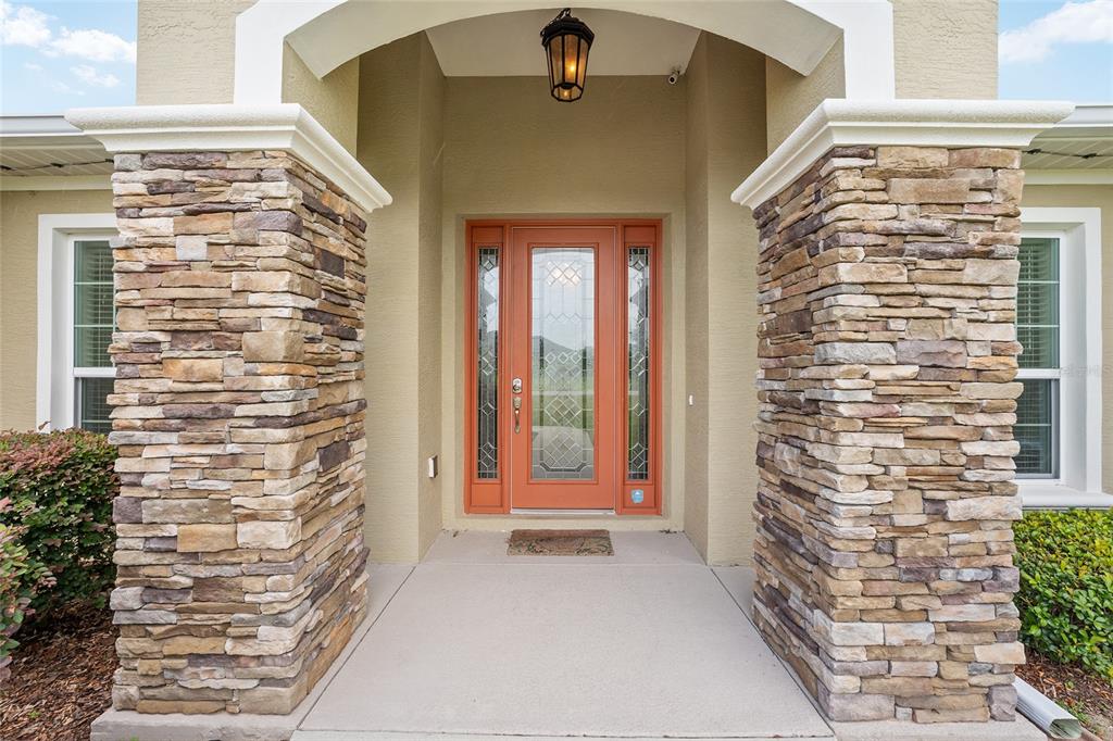 A front entryway features a glass-paneled orange door flanked by two stone-clad columns — 9654 SW 40TH TERRACE, OCALA, FL