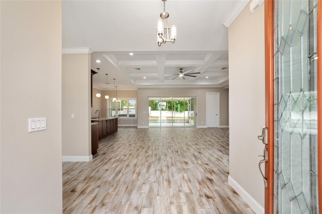 An entryway leads into an open-concept living area with wood-look tile flooring and coffered ceilings — 9654 SW 40TH TERRACE, OCALA, FL