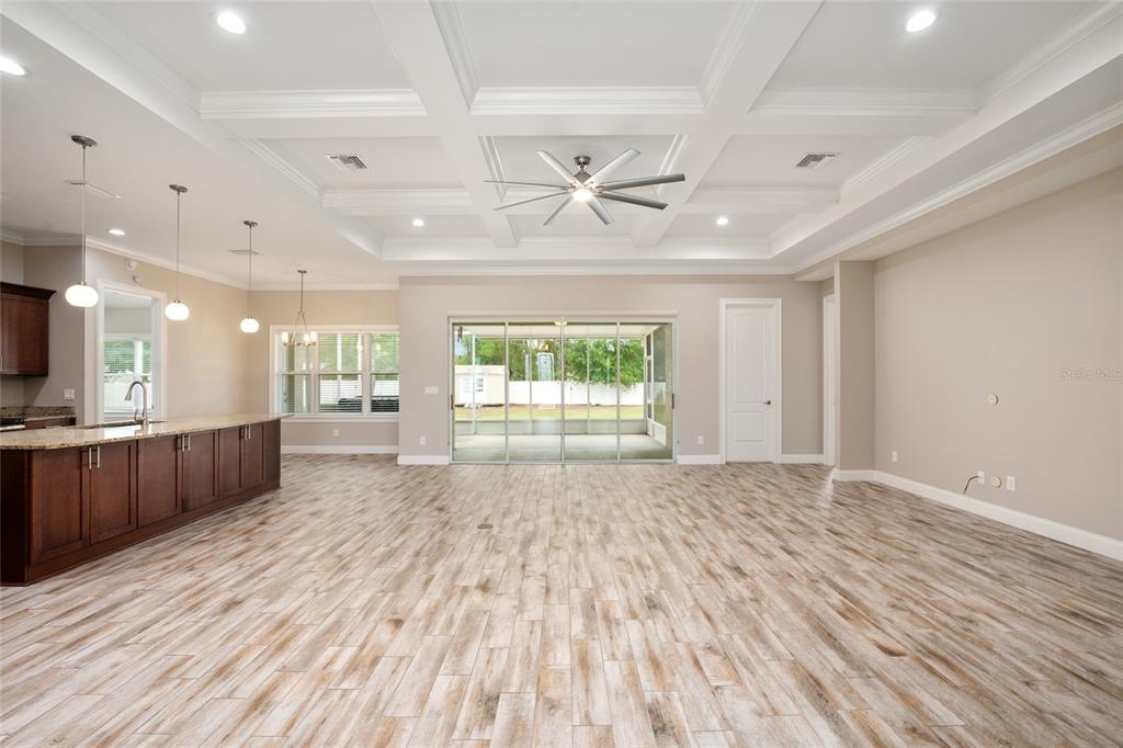 An open-concept kitchen and living area features wood-look tile flooring and a coffered ceiling — 9654 SW 40TH TERRACE, OCALA, FL