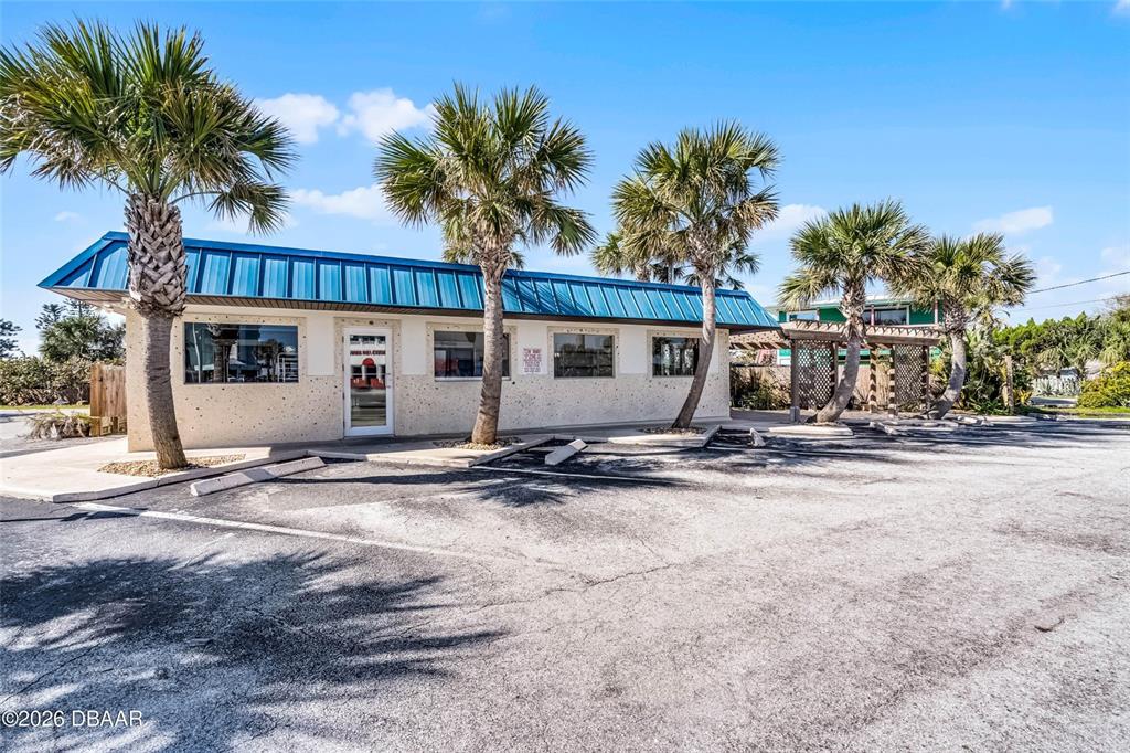 A one-story commercial building with a blue metal roof and palm trees in front — 819 SR A1A HIGHWAY, NEW SMYRNA BEACH, FL